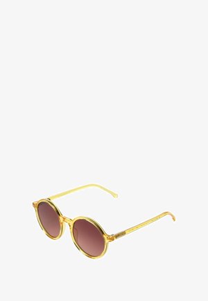 Lunettes de soleil rondes avec une monture jaune translucide et des verres dégradés marron. Fines branches avec des motifs gravés, texture lisse sur toute la surface.