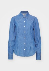 Ljusblå denimskjorta med spetsig krage, långa ärmar och knäppning framtill. Innehåller subtila sömdetaljer och rundad nederkant.