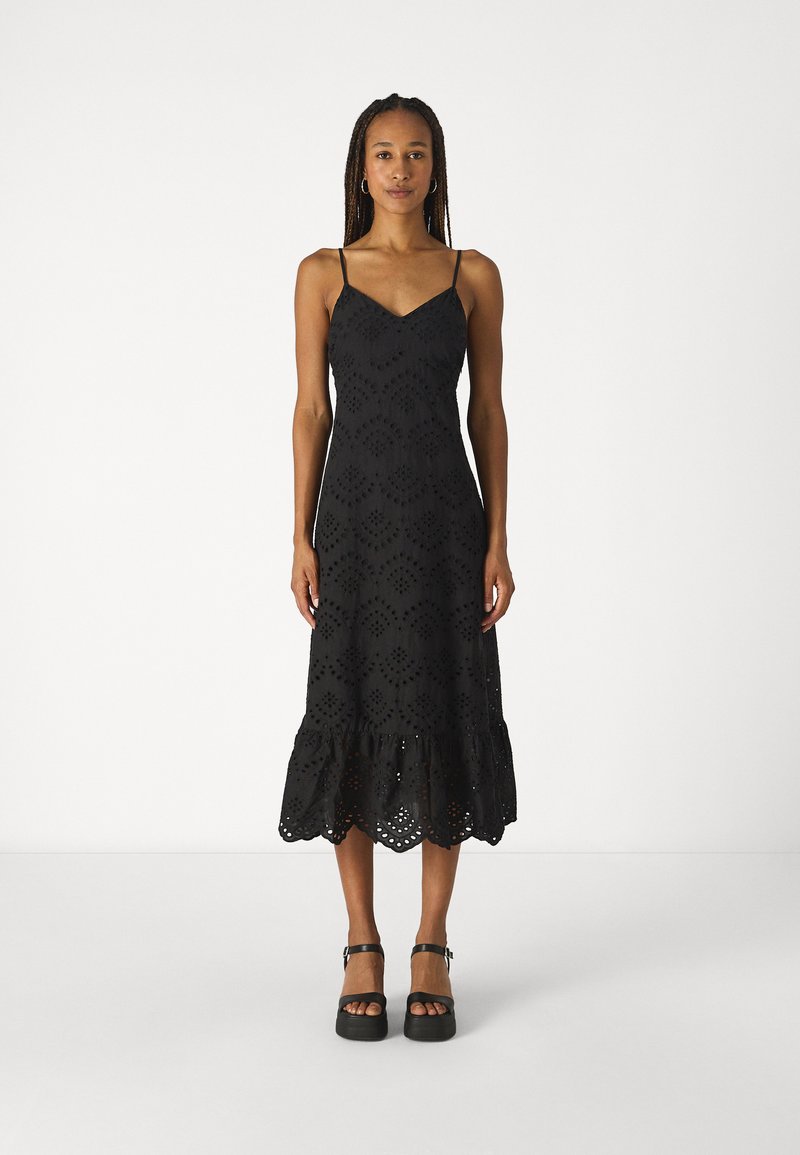 Vestido preto sem mangas com decote em V, apresentando padrões de bordado à vista, uma barra godê e uma borda rendada na parte inferior.