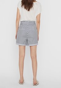 Raidalliset shortsit, jotka on valmistettu kevyestä kankaasta; korkeavyötäröinen malli, kahdella takataskulla ja räätälöidyllä istuvuudella mustavalkoisissa raidoissa.