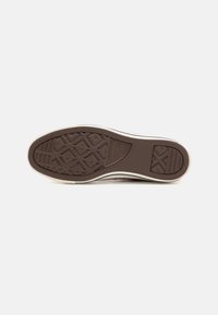 Semelle de chaussure en caoutchouc marron avec un motif de diamant, bordée d'une finition blanche, dotée de crêtes proéminentes et d'une surface texturée pour une meilleure adhérence.