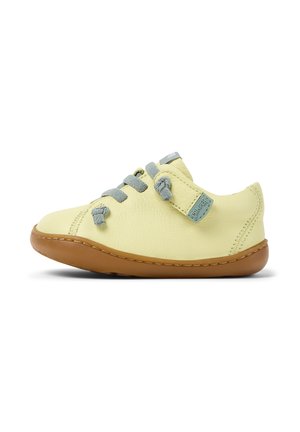 Scarpe in pelle gialla con lacci grigi e una fascia in velcro, dotate di una suola in gomma marrone, punta rotonda e leggeri dettagli di cucitura.