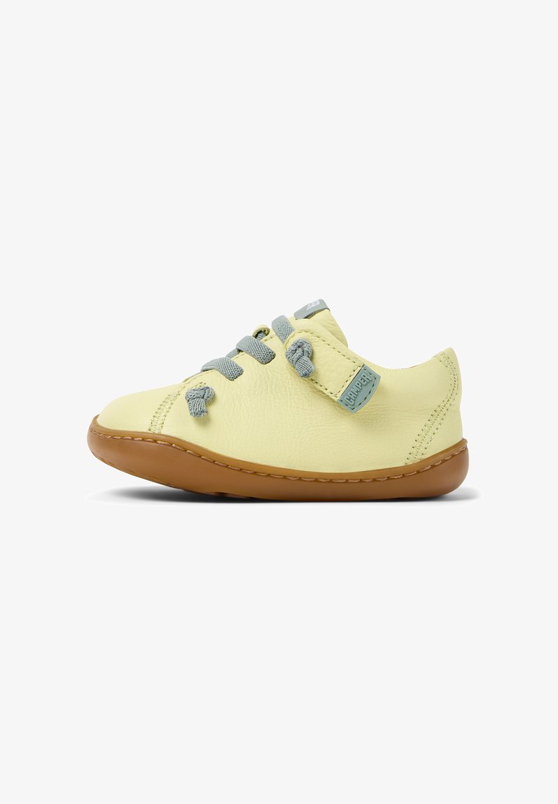 Scarpe in pelle gialla con lacci grigi e una fascia in velcro, dotate di una suola in gomma marrone, punta rotonda e leggeri dettagli di cucitura.