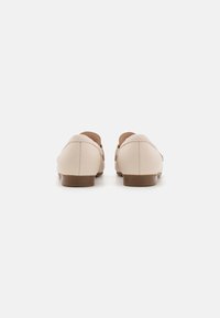 Beige leren schoenen met een gladde textuur, korte zolen en ronde hakken. Beschikt over zijopeningen en subtiele stiksels.