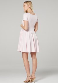 Rosa Kurzarmkleid mit tailliertem Oberteil und ausgestelltem Rock. Weicher Stoff mit glatter Textur. Klassischer Rundhalsausschnitt und knielanger Saum.