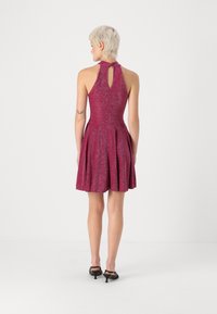 Ροζ λαμπερό φόρεμα με εφαρμοστό κορσέ, φουσκωτό κεντρικό μέρος και λεπτομέρεια με κλειστό πίσω. Το ύφασμα έχει λεία υφή και διακριτική λάμψη.