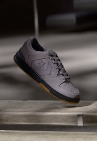 Graue Wildleder-Sneaker mit schwarzer Gummisohle, Schnürdesign, Stern-Logo an der Seite und perforierter Zehenpartie für Atmungsaktivität.