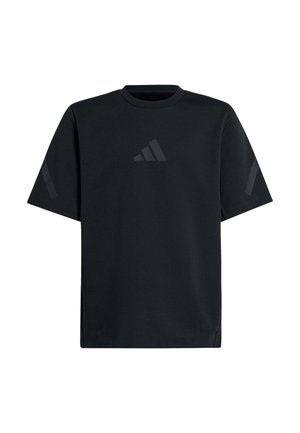 Dos niños sonrientes que llevan camisetas negras de manga corta y pantalones, de pie uno al lado del otro sobre un fondo blanco.