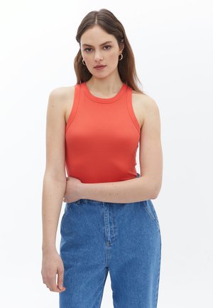Top sin mangas rojo acanalado con escote redondo, combinado con jeans azules de cintura alta, que presentan un ajuste relajado y textura de denim.