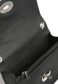 Svart läderhandväska med insida som har en ficka med dragkedja, silverfärgad hårdvara och en texturerad magnetstängning. Etikett synlig inuti.