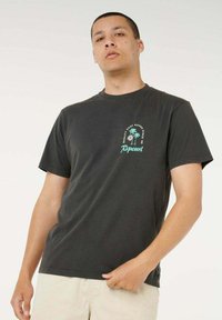 T-shirt nera in cotone con maniche corte, caratterizzata da un design con palme pastello e testo sul lato sinistro superiore del petto; vestibilità morbida.