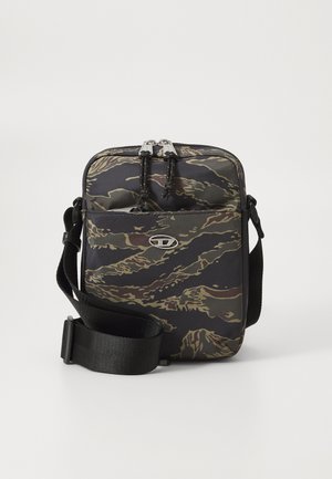 Small crossbody bag with black, brown, and green camouflage pattern, front pocket, double zipper, and adjustable black strap.