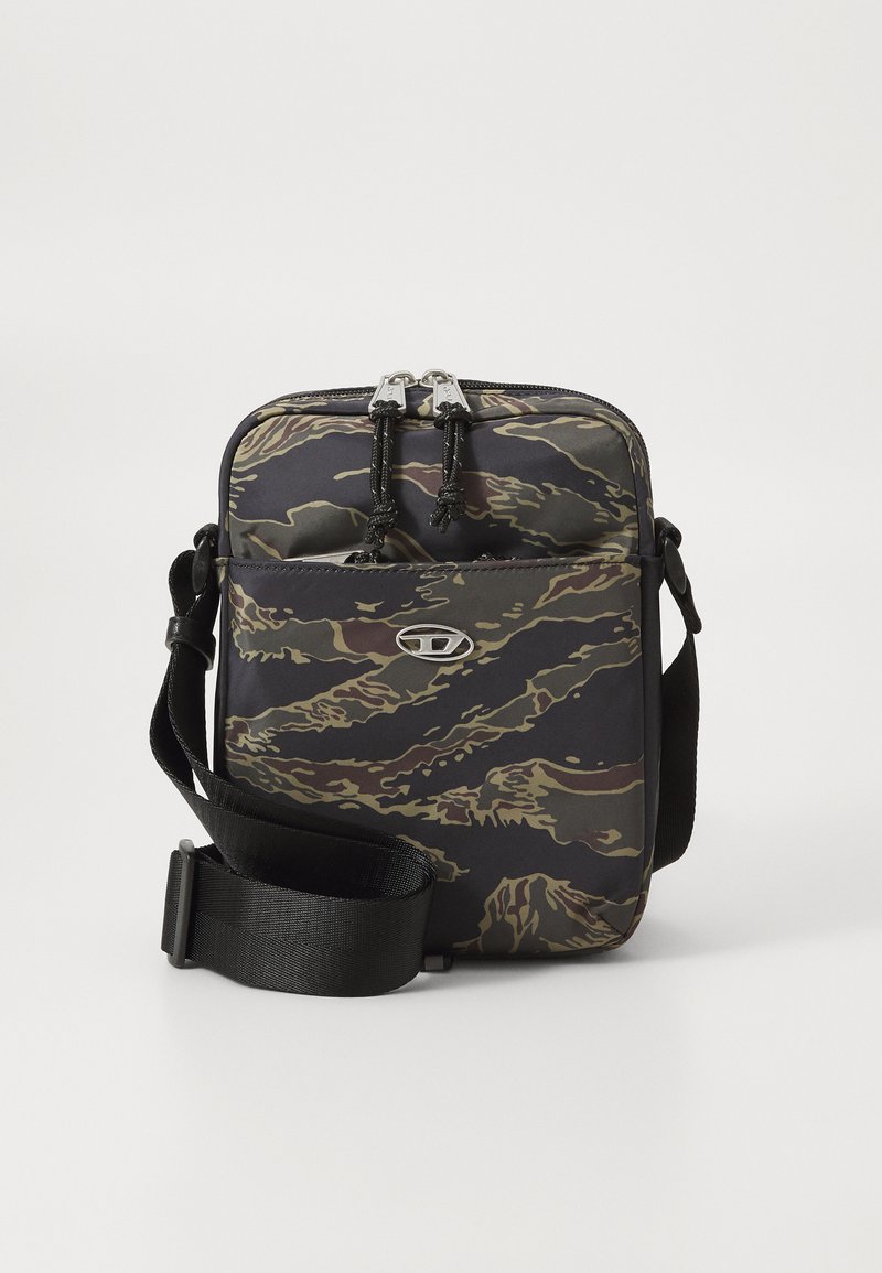 Piccola borsa a tracolla con motivo camouflage nero, marrone e verde, tasca frontale, doppia cerniera e tracolla nera regolabile.