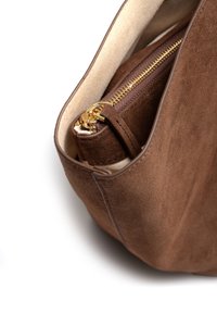 Brązowa zamszowa torebka z detalem złotego zamka błyskawicznego, gładkimi skórzanymi akcentami i wewnętrzną kieszenią. Miękka tekstura, zaokrąglony kształt i neutralny kolor.