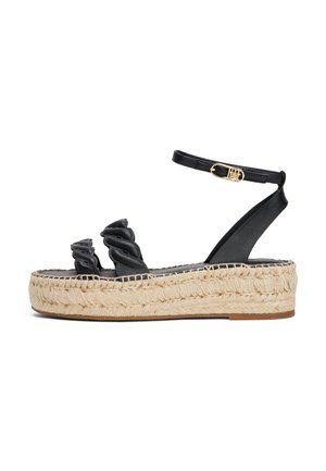 Sandales espadrilles noires avec des brides en cuir torsadées, une semelle en jute enveloppée et une bride de cheville réglable avec une boucle dorée.