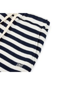 Marinblå och vit randig tyg med dragsko i midjan; har en liten logotyp på det nedre hörnet och en mjuk, strukturerad yta.