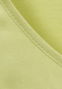 Lichtgroene stof met een gladde textuur, voorzien van een naaddetail. Het materiaal lijkt rekbaar met een subtiele glans.