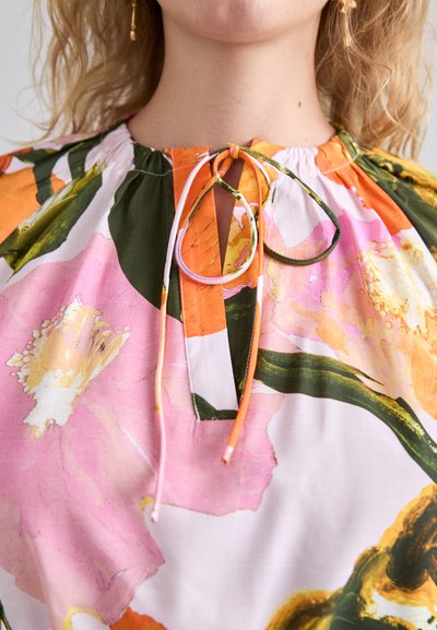 Blusa floreale colorata con motivi rosa, arancio e verde. Collo rotondo con chiusura a fascia. Tessuto morbido con una vestibilità rilassata.