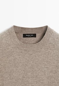 Pull beige col rond avec col côtelé et étiquette de marque Massimo Dutti cousue à l'intérieur de l'encolure.
