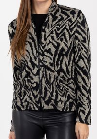 Cardigan a zip in nero e beige con un design a strisce zebrate testurizzate, maniche lunghe e tasche frontali.