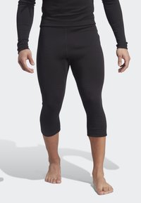 Black stretch capri leggings made from a soft, elastic material, featuring a smooth texture and a fitted design, ending below the knee.