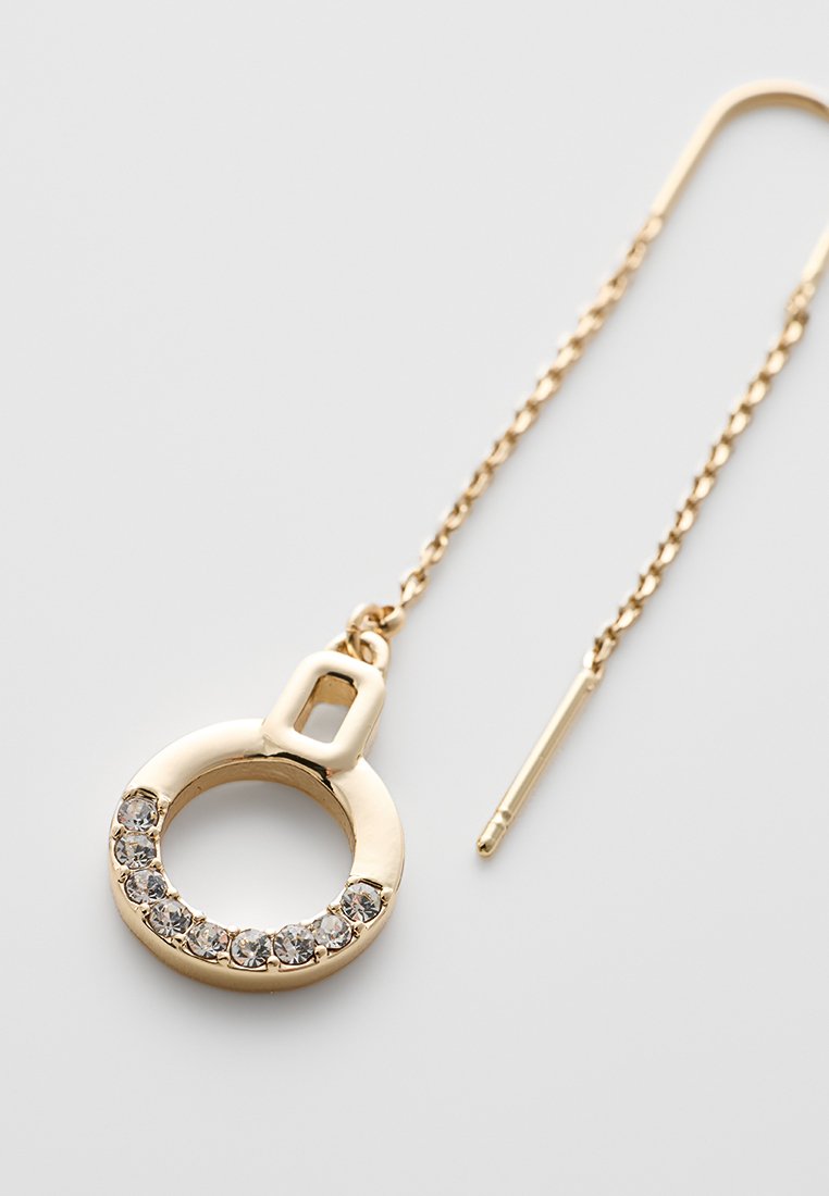 Boucles d'oreilles circulaires dorées avec un centre creux et une fermeture sécurisée. Présente une ligne de strass brillants le long du bord. Style chaîne.