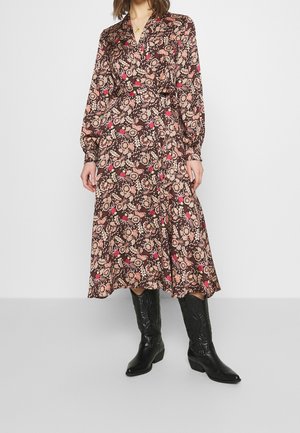 Abito avvolgente a maniche lunghe con stampa floreale nei toni del marrone, rosa e crema. Presenta una vita cin cin e un orlo fluido; abbinato a stivali da cowboy neri.