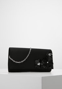 Bolso de mano negro con un diseño elegante, hecho de tela texturizada. Presenta adornos florales y una correa de cadena plateada.