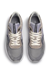 Zapatillas gris y moradas con material de malla y ante, con cordones crema, lengüeta acolchada y suela de goma. Logotipo en la lengüeta.