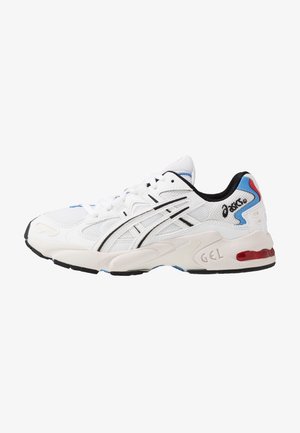 Sneaker atletica bianca con materiale in rete, accenti neri e blu, suola imbottita con marchio "GEL" e design della punta arrotondata.