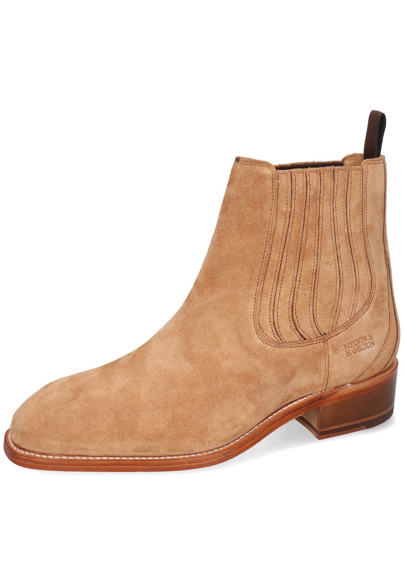 Bottine en daim beige clair avec panneaux latéraux en élastique et languette en marron. Présente un bout pointu et un talon en bois.