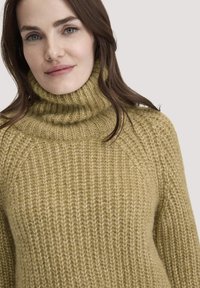 Beige gestrickter Rollkragenpullover mit strukturiertem Rippmuster, hoher Kragen und lässiger Passform, aus weichem Garn.