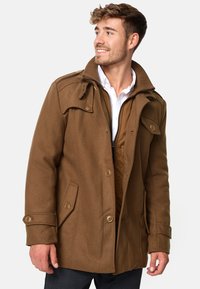 Manteau marron en mélange de laine avec un col montant, une fermeture éclair à l'avant et des accents de boutons. Comprend des poches latérales et une doublure intérieure matelassée.