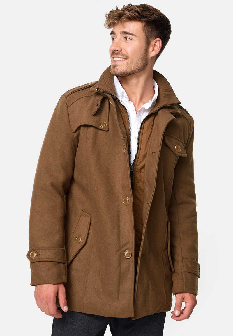 Manteau marron en mélange de laine avec un col montant, une fermeture éclair à l'avant et des accents de boutons. Comprend des poches latérales et une doublure intérieure matelassée.