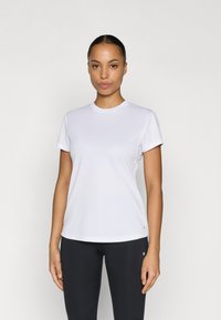 Weißes Sport-T-Shirt mit kurzen Ärmeln und Rundhalsausschnitt, glatter Textur und dezentem Logodetail am Saum; kombiniert mit schwarzen Leggings.