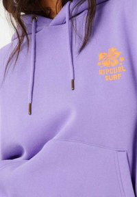 Paarse hoodie met een voorzak, trekkoorden met gouden uiteinden en een oranje bloemen- en merklolog ontwerp op de borst.