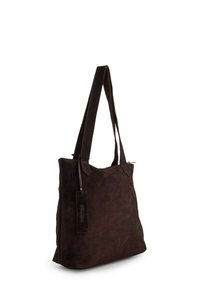 Bruine suède shopper met lange handvatten, rechthoekige vorm, minimalistisch ontwerp, voorzien van een klein label dat met een lusje is bevestigd.