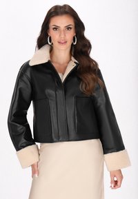 Giacca nera in pelle cropped con colletto e polsini in finta pelliccia, dotata di due tasche frontali e una superficie liscia.