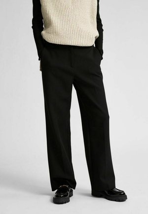 Zwarte wijde broek met een op maat gemaakte pasvorm, met een gladde textuur en van voren zakken, gecombineerd met een gebreide romige mouwloze top.