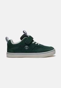 Dark green suede sneaker with white laces, Velcro strap, gray pull tabs, Timberland logo, and white rubber sole, shown in side view.