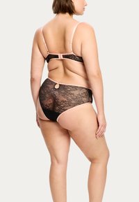 Ensemble de lingerie en dentelle noire avec des bretelles rose clair, présentant une fermeture à crochets et un détail en anneau décoratif dans le dos.