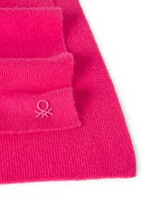 Světlá růžová pletená tkanina s ribbed texturou. Obsahuje malý růžový detail loga připomínajícího chobotnici. Hladký povrch.