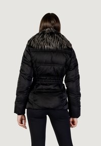Giacca a vento nera con colletto in pelliccia sintetica. Presenta vita elasticizzata, maniche lunghe e dettagli con tasche. Tessuto liscio e lucido.
