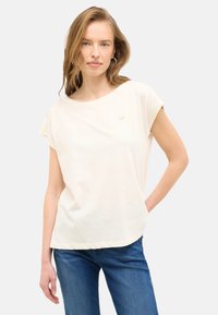 Hellbeige Kurzarm-T-Shirt mit Rundhalsausschnitt, aus weichem Stoff gefertigt. Verfügt über ein kleines goldenes Logo auf der Brust und einen lockeren Schnitt.