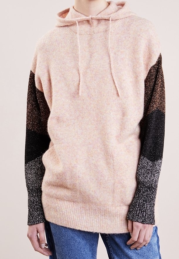 Rosa och svart huvtröja med en texturerad yta, som har varierande stickmönster och en avslappnad passform, som matchas med blå jeans.