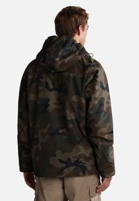 Giacca con cappuccio a fantasia mimetica nelle tonalità di verde e marrone. Realizzata in materiale leggero e liscio, presenta un cappuccio con cordino e una vestibilità ampia.