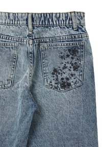 Jeans in denim di colore azzurro chiaro con texture sbiadita, dotati di una vita, due tasche posteriori e un motivo di schizzi d'inchiostro scuro su una tasca.