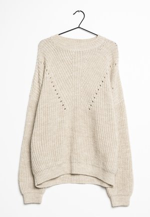 Pull en maille épaisse couleur crème avec manches longues suspendu à un cintre noir sur fond blanc.