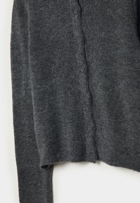 Cardigan tricoté gris foncé à manches longues avec six petits boutons ronds sur le devant, suspendu sur un fond blanc.