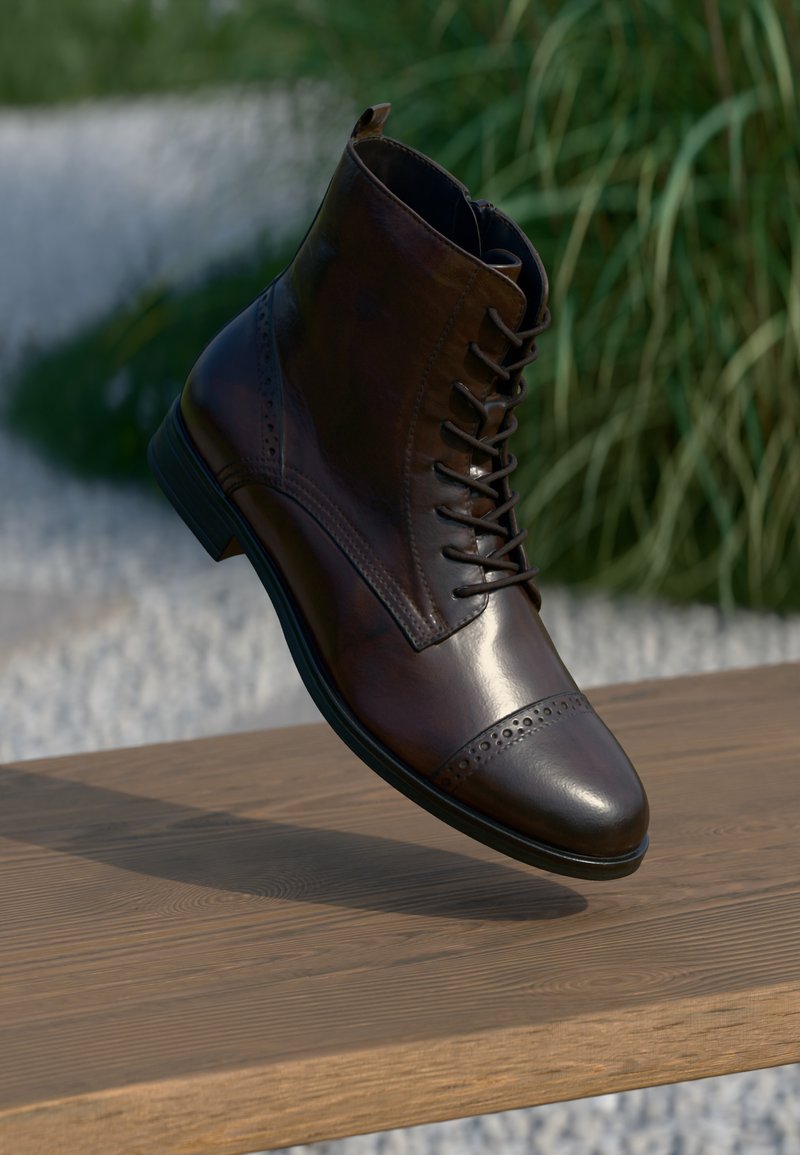 Brun læder ankelstøvle med rund tå, brogue-detaljer og snørebånd, som har en glat overflade og gummisål.